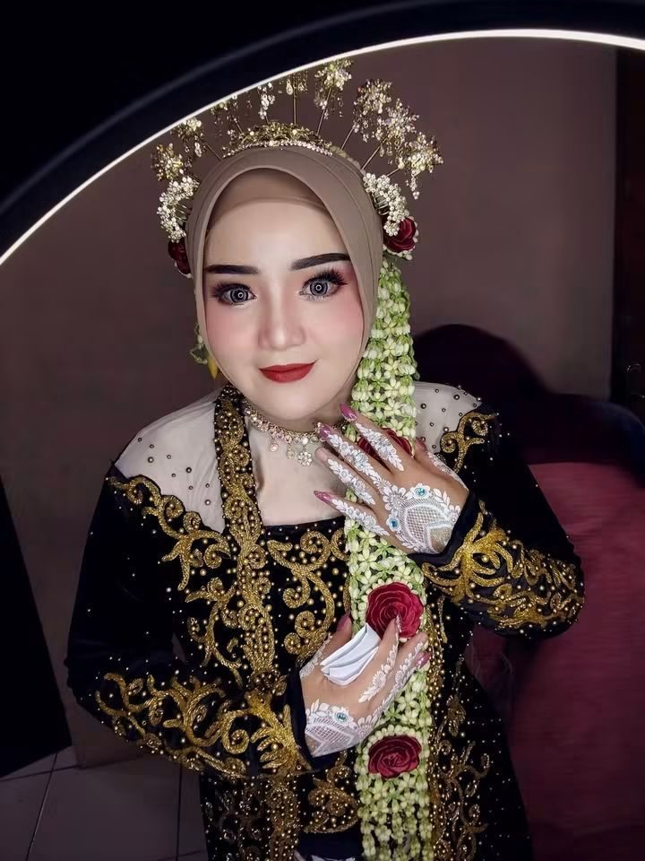 Potret pengantin dengan mahkota emas, kalung berlapis, dan riasan mata hangat.
