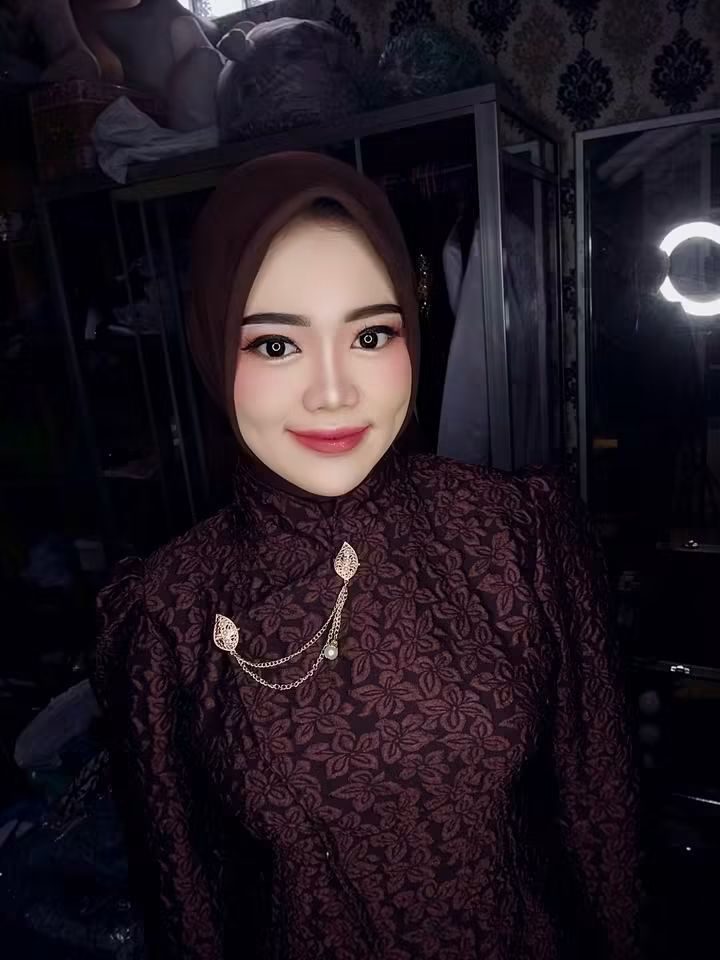 Potret riasan dengan kerudung cokelat dan kebaya brokat bersulam bros.