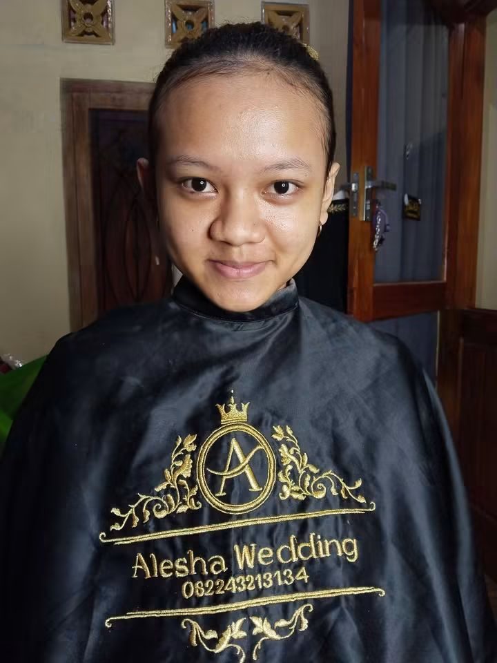 Seorang perempuan tanpa riasan mengenakan cape rias Alesha, sesaat sebelum sesi dimulai.